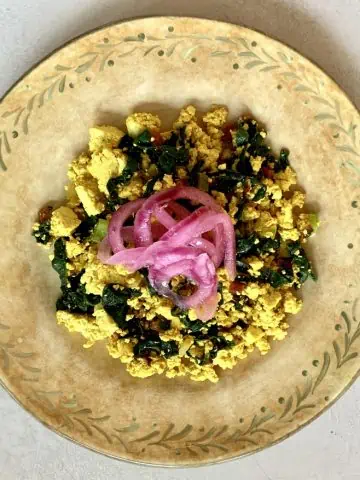 Tofu Scramble with Swiss Chard and topped with Pickled Onions on a decorative plate