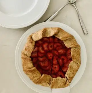 Vegan Strawberry Galette on a white plate with first slice cut into
