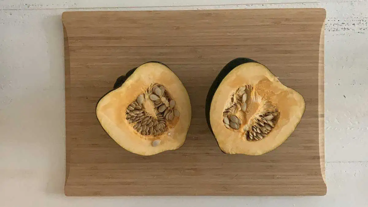 Acorn squash sliced in half on a cutting board.