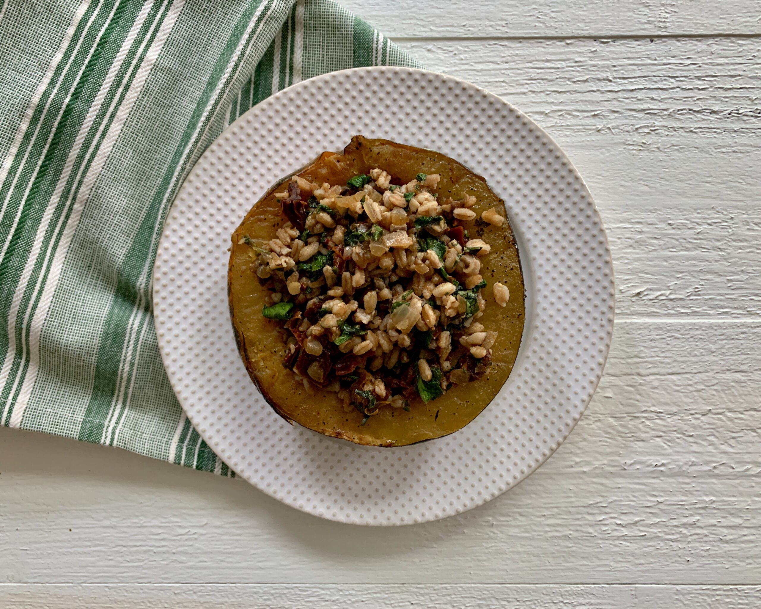 Vegetarian stuffed acorn squash with farro stuffing on a plate.