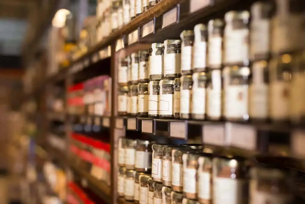 Large assortment of natural seasonings and spices in glass jars on store counter