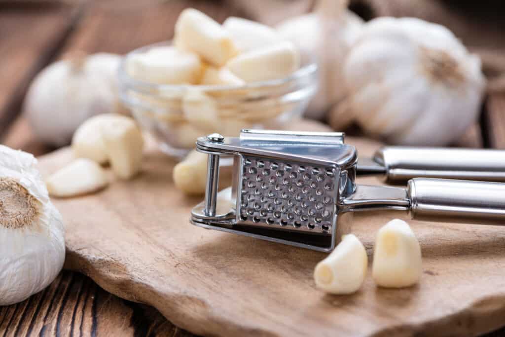 Garlic Press (with fresh Garlic) on rustic wooden background