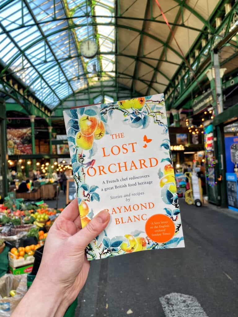 The Lost Orchard book being held up in a local market