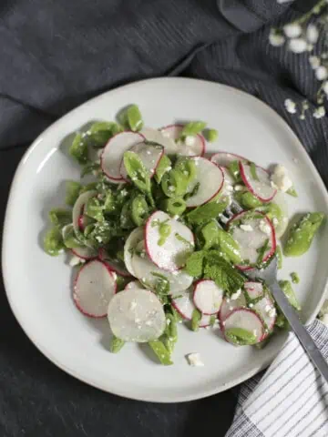 snap pea salad with radishes, mint and feta on a plate