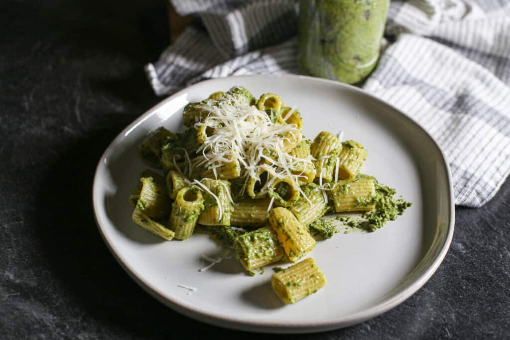 Walnut and carrot top pesto over pasta on a plate