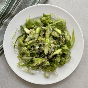 spring asparagus pea salad on a white plate with a napkin alongside it