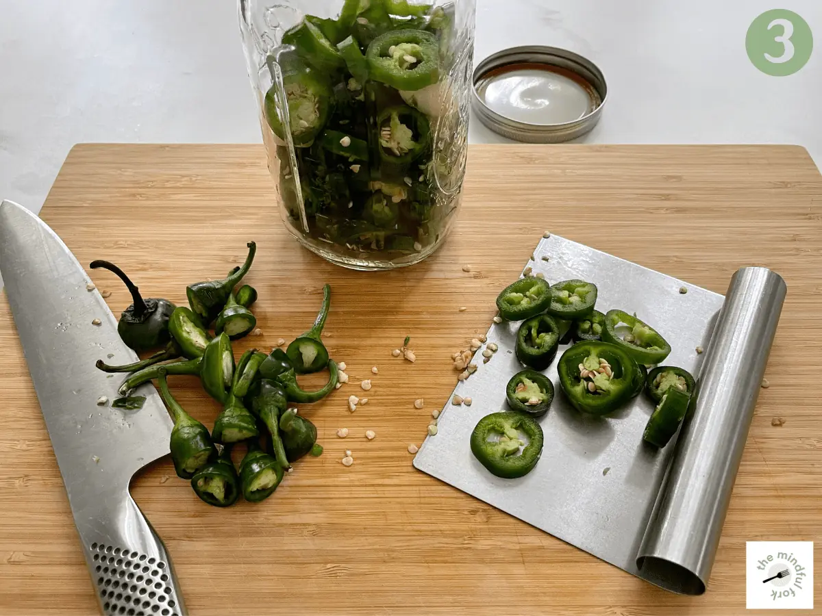 Jalapeno slices are added to the jar.