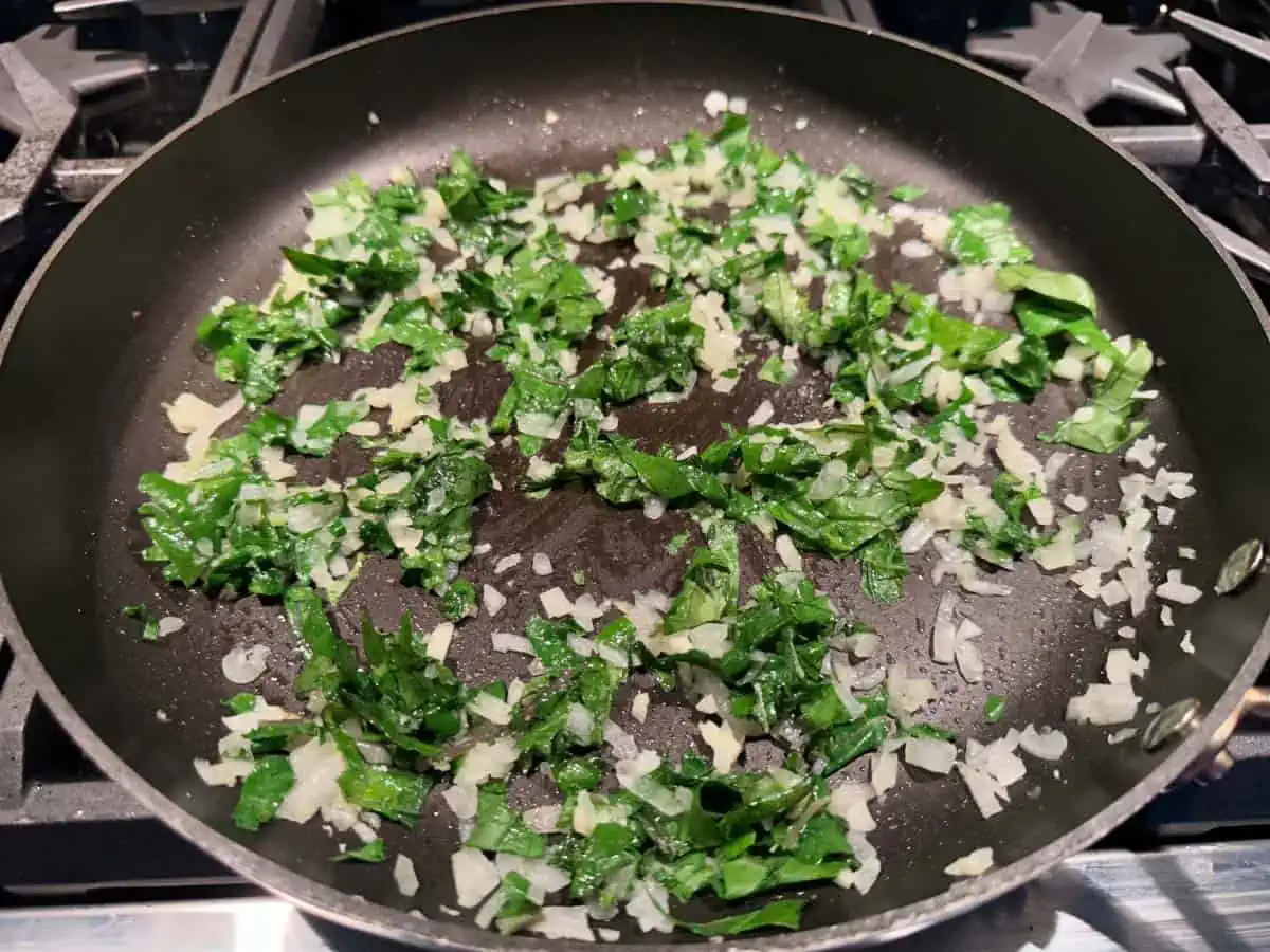 Kale, onions and garlic cooking in a pan.