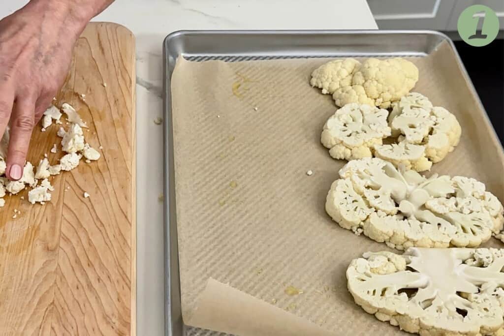 Sliced cauliflower is placed on a parchment lined baking sheet.