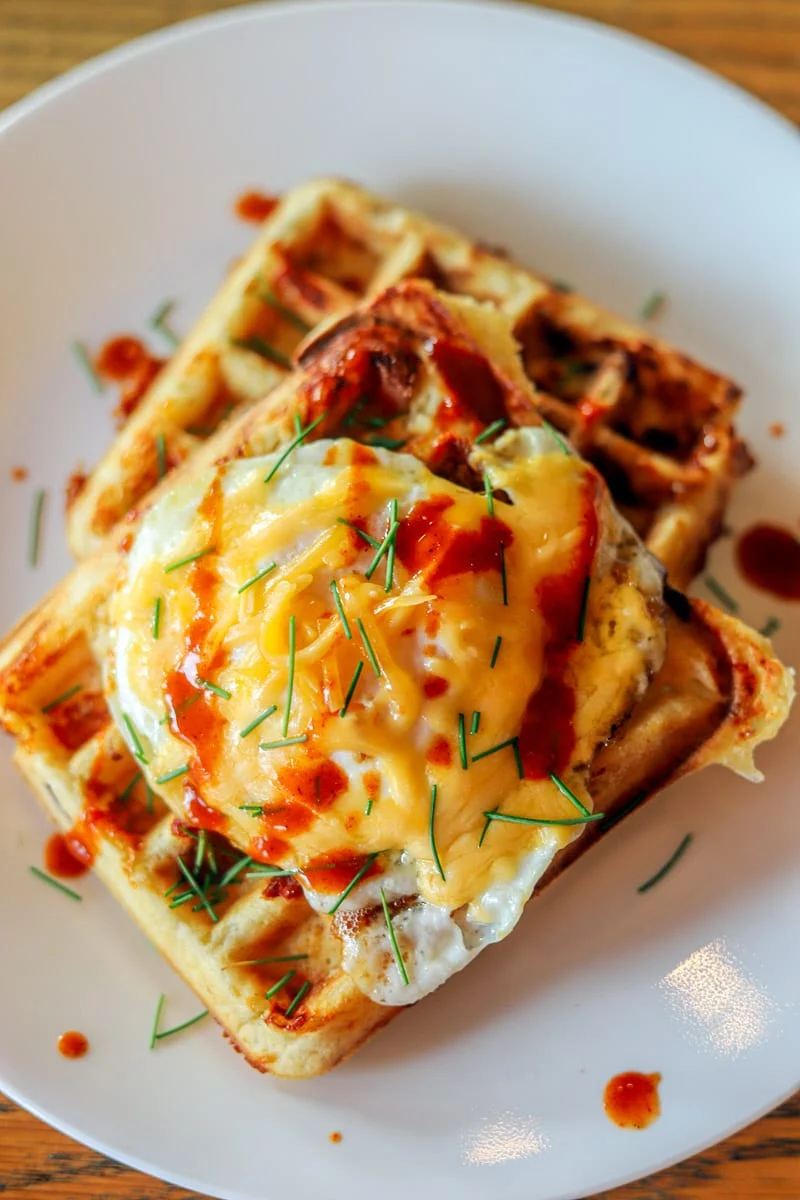 Waffles topped with a fried egg, chives and hot sauce.