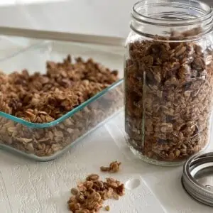 A container and jar of crunchy vegan granola on the table.