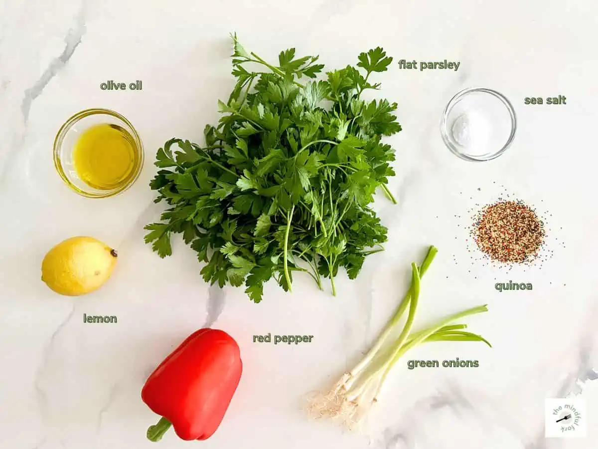 Ingredients to make quinoa tabouleh on the table with text labels.